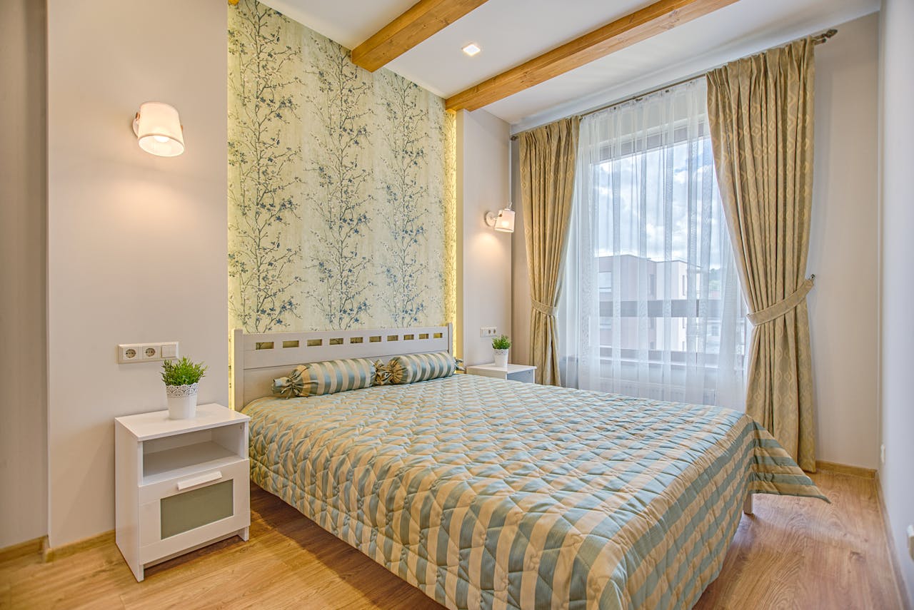 A luxurious and contemporary bedroom design with patterned wallpaper and natural lighting, located in Vilnius, Lithuania.